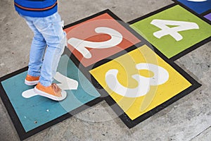 Young kid playing hopscotch alone