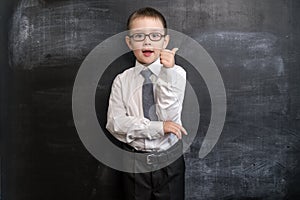 Young kid`s standing near a blackboard showing YES sign. Back to school concept. Smart and clever preschool boy.