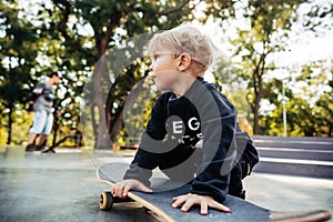 Young kid sitting in the park on a skateboard.