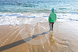Young kid standing on a stormy beach in the winter