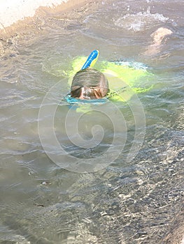 Young kid swimming with goggles and snorkel