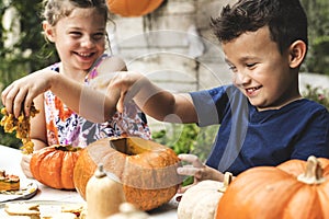 Young kids carving Halloween jack-o`-lanterns