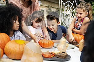 Young kids carving Halloween jack-o`-lanterns