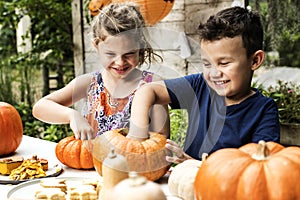 Young kids carving Halloween jack-o`-lanterns