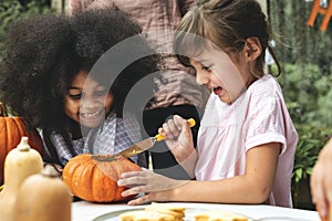 Young kids carving Halloween jack-o`-lanterns