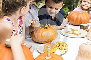 Young kids carving Halloween jack-o`-lanterns