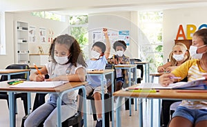Young kids learning in classroom after covid pandemic, wearing protective face masks. Little children sitting in school