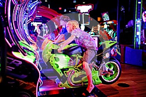 Young Kids Playing a Motorcyle Riding Game at the Neon Lights Arcade