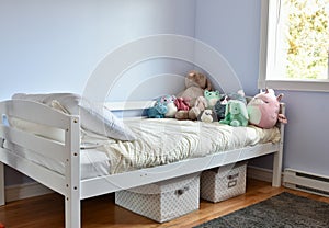 Young kids room with cute plush toys on bed and simple, easy storage baskets underneath