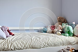 Young kids room with cute plush toys on bed and simple, easy storage baskets underneath