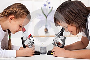 Young kids in science lab study samples under the microscope-focus on the boy face