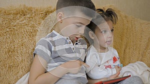 Young kids using a digital tablet todether in their living room