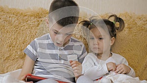 Young kids using a digital tablet todether in their living room