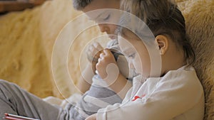 Young kids using a digital tablet todether in their living room