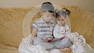 Young kids using a digital tablet todether in their living room