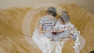 Young kids using a digital tablet todether in their living room