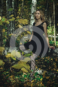 A young kind witch in a black dress with a black mask in a mystical forest in various poses. Art processing
