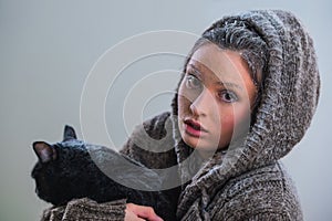 Young kind woman holding big black cat in frost