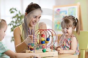 Young kindergarten teacher helping kids with toys