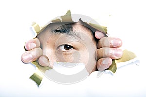 Young Korean man looking through ripped paper hole