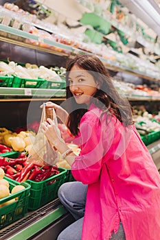 Young Korean woman shopping without plastic bags in grocery store. Vegan zero waste girl choosing fresh fruits and vegetables in