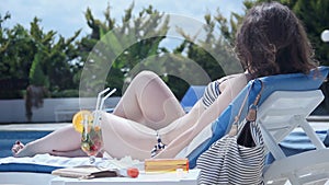Young lady in bikini sunbathing on deck chair, enjoying vacation
