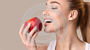 Young Lady Biting Red Apple On Beige Studio Background, Panorama