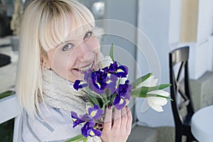 Young lady with a bouquet of violet irises and white tulips enjoying the spring