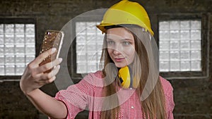 Young lady builder makes selphies on her smartphone, communication concept