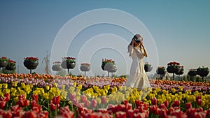 Young lady with camera making photo of beautiful tulips. Girl walking in park.