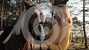 Young lady carefully puts the bridle on her horse before the horseback riding slow motion