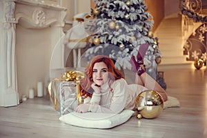 Young lady with curlu hair gifts by the fireplace near the Christmas tree. New year concept