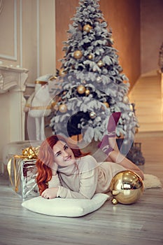 young lady with curlu hair gifts by the fireplace near the Christmas tree. New year concept