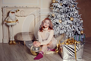 young lady with curlu hair gifts by the fireplace near the Christmas tree. New year concept