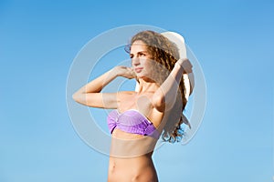 Young lady with curly hair and hat looking far