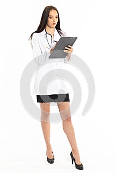 A young lady doctor holds a board with a clip and writes down her observations with a pen