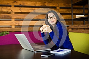 Young lady drink coffee at her working space in modern office.