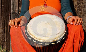 Young lady drummer with her djembe drum on rustic wooden door background