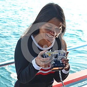 Young lady enjoys looking at photos on an underwater camera of her scuba diving.