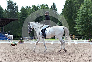 Young lady equestrian in dress uniform riding horseback on arena