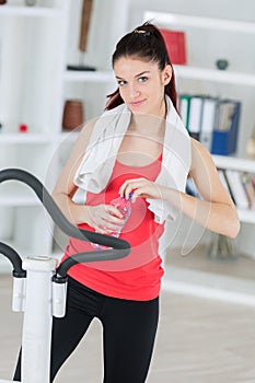 young lady exercising at home stopping for drink water