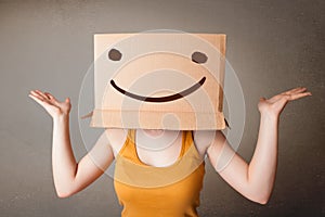 Young lady gesturing with a cardboard box on her head with smile