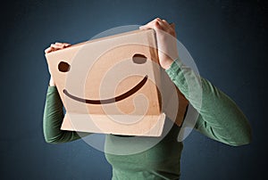 Young lady gesturing with a cardboard box on her head with smile