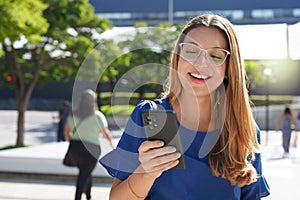 Young lady with glasses checking her mobile phone outdoors