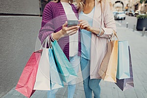 Young lady and her mother using at smartphone on the street