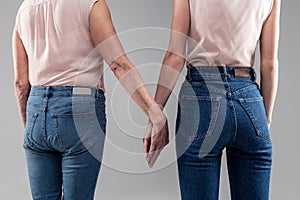 Young lady and her senior mother wearing blue jeans and nude tops