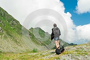 Young lady hiker with backpack sitting on mountain