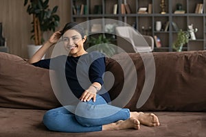 Young lady of indian ethnicity relax on couch look aside