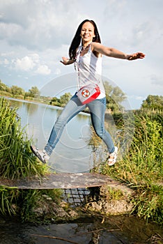 Young lady jumping by the lake