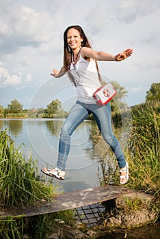 Young lady jumping by the lake